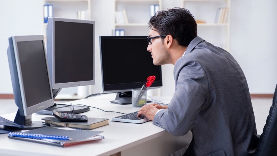 man using multiple computer monitors with poor posture